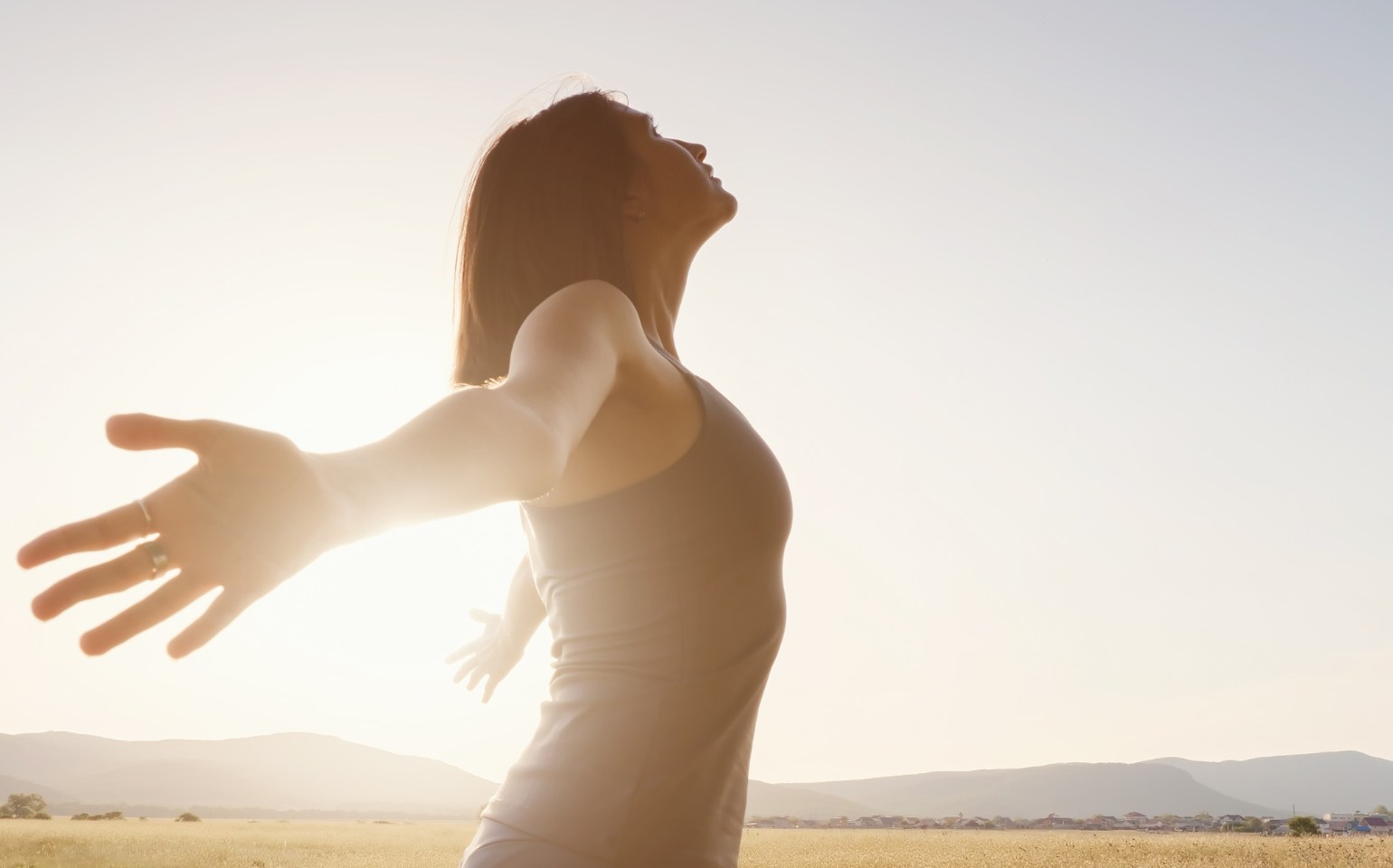 Detox-Woche Ayurveda & Yoga. Frau die die Arme ausbreitet im Sonnenlicht